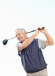 Sporty senior man swinging a golf club against clear sky