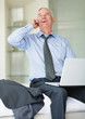 Laughing matured man over a cellphone with laptop