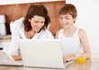 Photo: Happy mother assisting her son while using laptop at home Happy mother assisting her son while using laptop at home