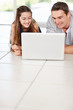 Foto: Smiling little girl with his father while looking at laptop Smiling little girl with his father while looking at laptop