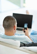 Man with a laptop while looking at his mobile phone at home