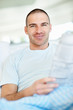 Photo: Happy middle aged male reading newspaper at home Happy middle aged male reading newspaper at home