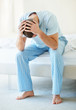 Tensed middle aged man with hands on head while sitting in bed