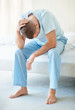 Stressed man with hands on head while sitting in bed