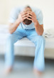 Stressed middle aged man with hands on head sitting in a sofa