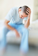 Depressed middle aged man with hand on head sitting in a sofa