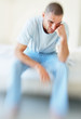Tensed middle aged man sitting in a bed at home