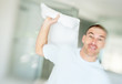 Middle aged man playing a pillow fight with you