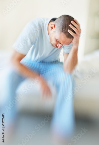 Photo: Depressed middle aged man with hand on head sitting in a sofa Depressed middle aged man with hand on head sitting in a sofa