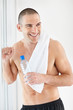Shirtless middle aged man holding a bottle in hand smiling