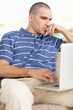 Thoughtful middle aged man looking at his laptop screen at home