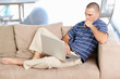 Thoughtful middle aged man with laptop while sitting in couch