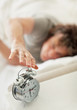 Mature man snoozing an alarm clock while lying in bed