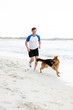 Photo: Healthy young guy running with his dog on beach Healthy young guy running with his dog on beach