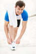 Happy young man tying his shoe's lace