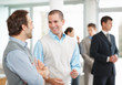 Young man talking to his colleague with people in background