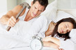 Couple in bed - Young man with hammer about to hit the alarm clo