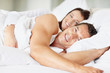 Foto: Young couple lying on bed and smiling Young couple lying on bed and smiling