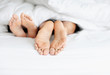 Feet of a couple resting on bed