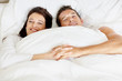 Romantic young ouple in bed holding hands