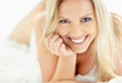 Beautiful young lady smiling while lying on the bed