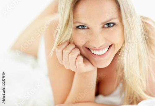 Foto: Beautiful young lady smiling while lying on the bed Beautiful young lady smiling while lying on the bed