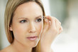 Pretty female using tweezers to pull out unwanted hair