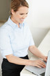 Happy young female executive using a laptop at desk