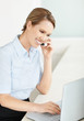 Happy young executive using a laptop and mobile phone