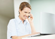 Cheerful executive talking on cellphone while using a laptop
