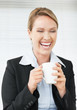 Laughing young business woman holding a cup of coffee