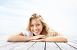 Happy young girl lying on a porch against the sky
