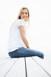 Smiling female sitting on a porch against the bright sky