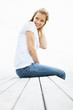 Smiling casual female sitting on a wooden porch