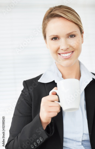 Photo: A attractive business woman holding a cup of tea or coffee A attractive business woman holding a cup of tea or coffee