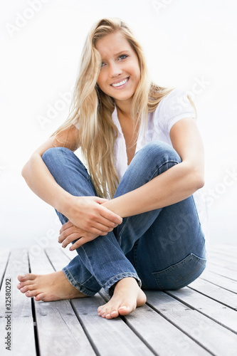 Foto: Happy young woman hugging her knees on a porch Happy young woman hugging her knees on a porch