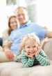 Foto: Cheerful boy lying in sofa while his blur parents in background Cheerful boy lying in sofa while his blur parents in background
