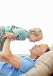Mature man holding his son while lying in sofa