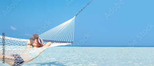 Foto: Happy woman relaxing on hammock at a beach Happy woman relaxing on hammock at a beach