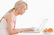 Beautiful female having her breakfast while working on a laptop