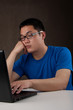 bored and tired young asian man working with his computer