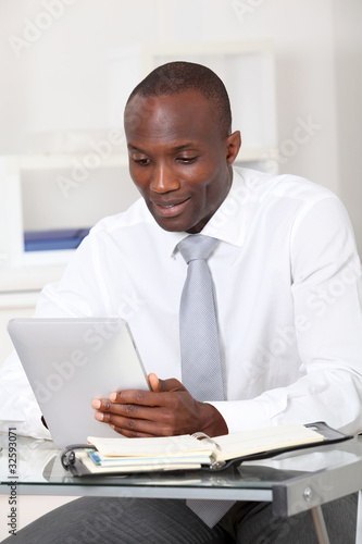 Photo: Businessman using electronic tablet in office Businessman using electronic tablet in office