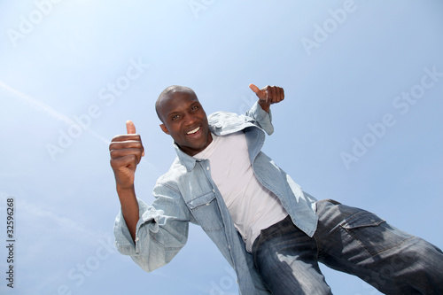 Photo: Man showing thumbs up with blue sky Man showing thumbs up with blue sky