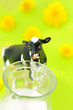 A cow and a milk jug against a bright green background