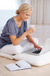 Beautiful young woman using laptop holding a coffee cup
