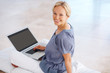 Pretty young lady sitting on floor with a laptop