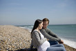 A pregnant woman and her partner sitting on the beach
