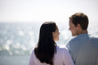 A pregnant woman and her partner standing on the beach