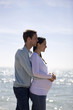A pregnant woman and her partner embracing on the beach