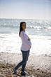 A pregnant woman walking on the beach, smiling